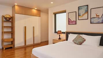 A hotel room with a bed, a nightstand, a lamp, a wardrobe, and artwork on the wall.