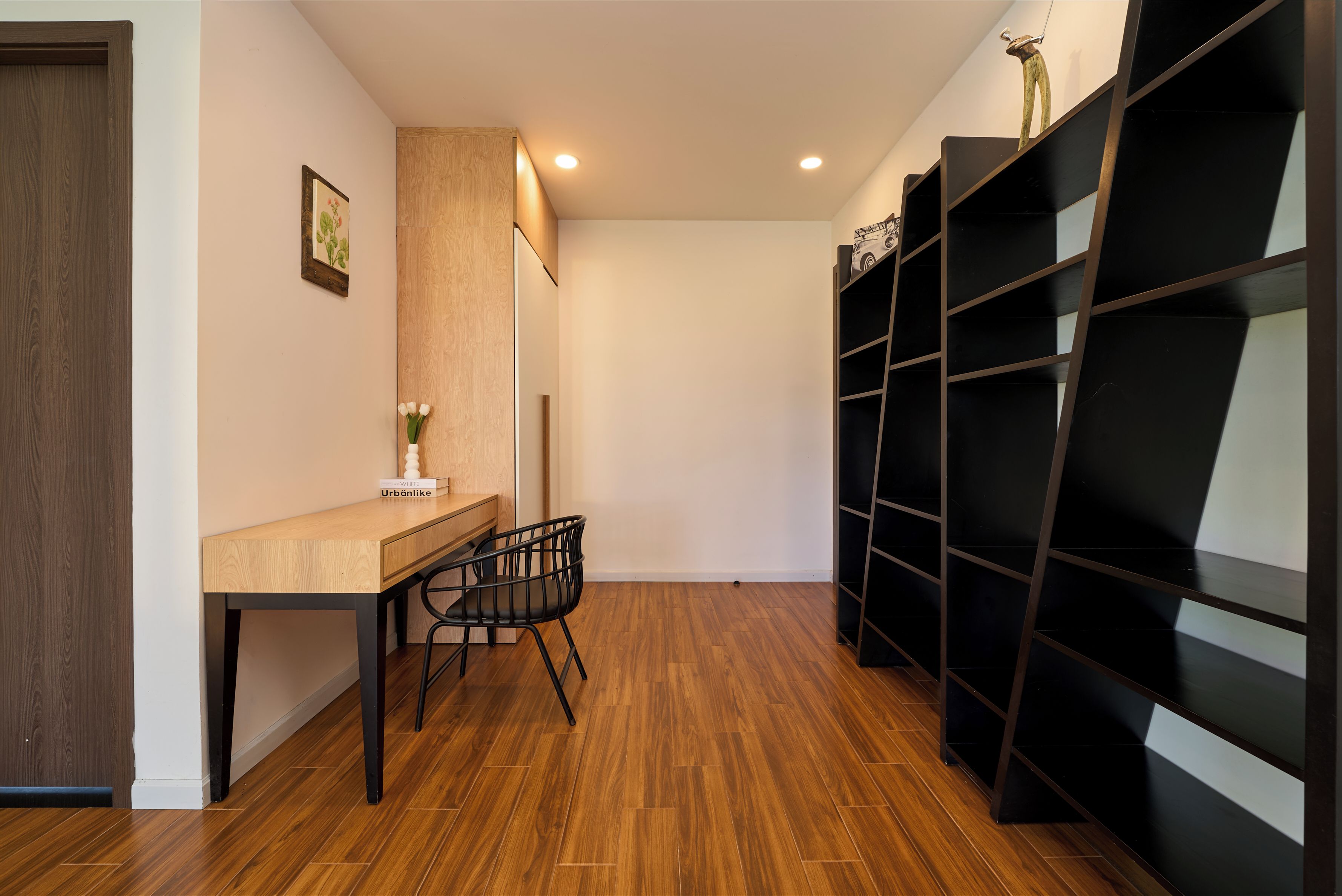 Una camera moderna con una scrivania in legno, una sedia e un'unità scaffali nera.