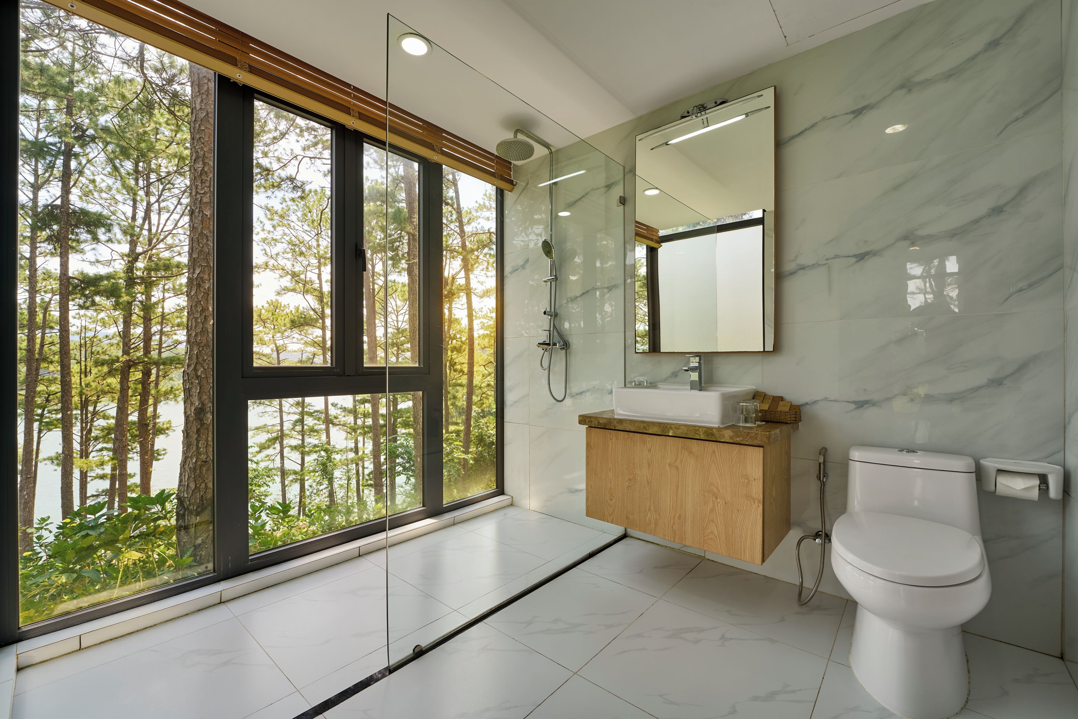 A modern bathroom with a large window, a shower, and a toilet.