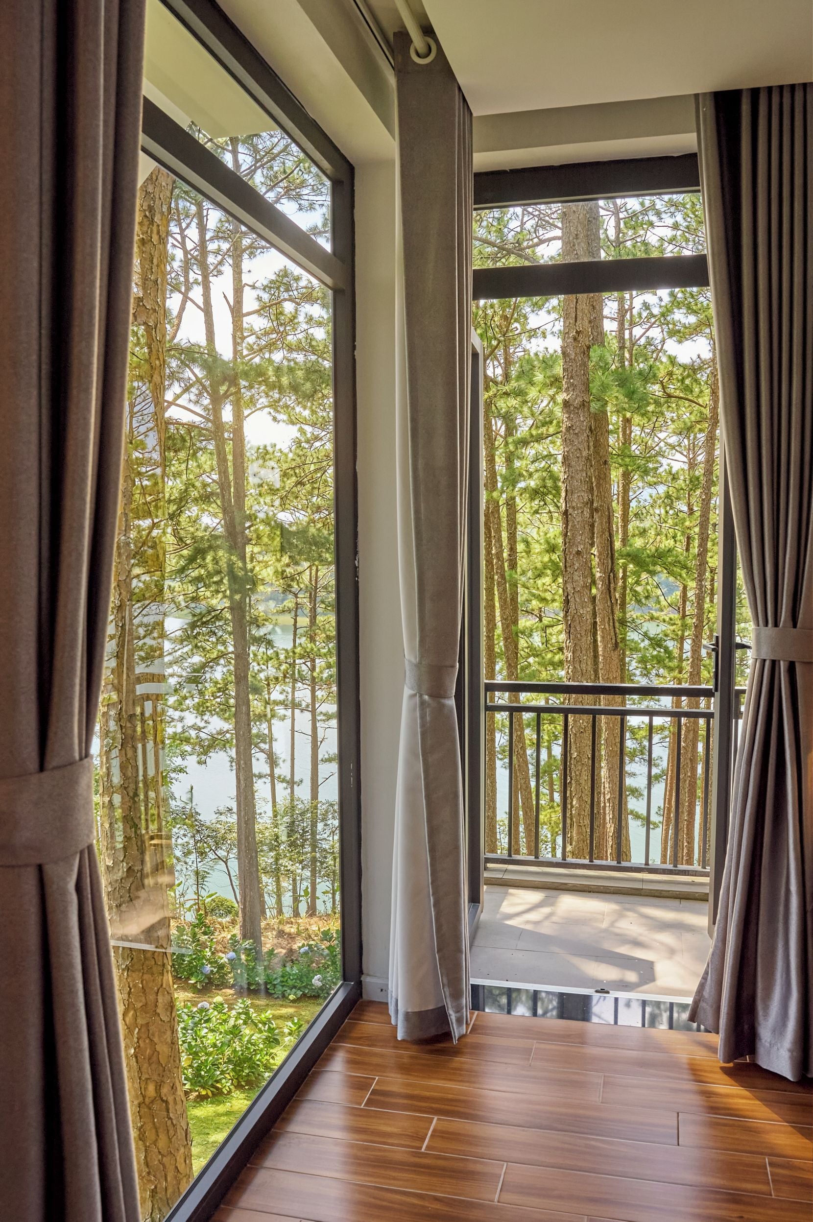 A room with large windows offering a view of a forest and a lake.