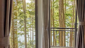 A room with large windows offering a view of a forest and a lake.