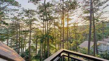 A residential area with tall pine trees, a wooden deck, and a house with a tiled roof.