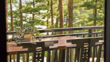 A dining area with a table and chairs, overlooking a forested area.