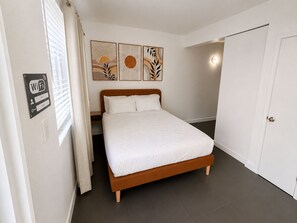 A bedroom with a bed, a door, a wall-mounted artwork, and a Wi-Fi sign. - Modern Studio with Pool near Miami Beach (Miami)