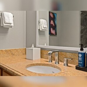 A bathroom with a granite countertop, a sink, a mirror, and a towel rack. - Club Wyndham Grand Desert (Las Vegas)
