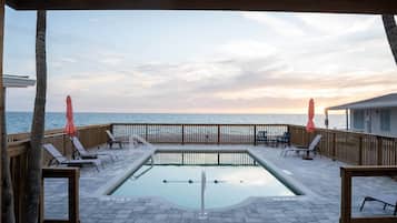 Un espace piscine avec vue sur l’océan, une terrasse en bois et des chaises longues.