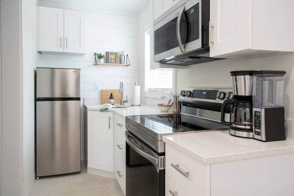 A modern kitchen with stainless steel appliances, including a refrigerator, microwave, oven, and coffee maker.