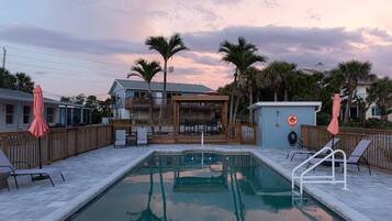 A swimming pool with a wooden deck, lounge chairs, and a lifebuoy.