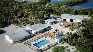A beachfront property with a swimming pool, multiple buildings, and a dock.