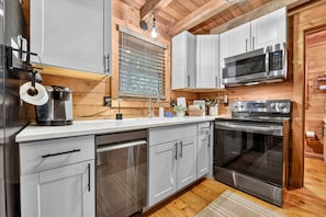 Une cuisine moderne dotée d’appareils électroménagers en acier inoxydable, de meubles de rangement en bois et d’un four encastré.