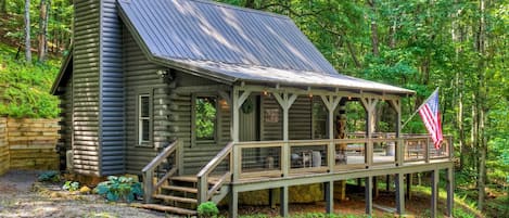 Una baita rustica con veranda e bandiera, immersa in una fitta foresta.