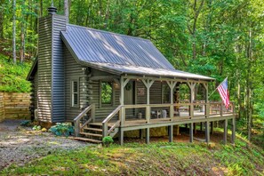 Una baita rustica con veranda e bandiera, immersa in una fitta foresta.