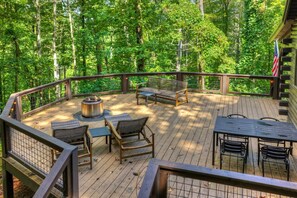 Una terrazza con mobili da esterno, un braciere e vista su una foresta.