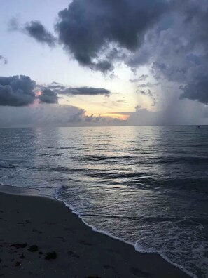 Uma praia com ondas e céu nublado.