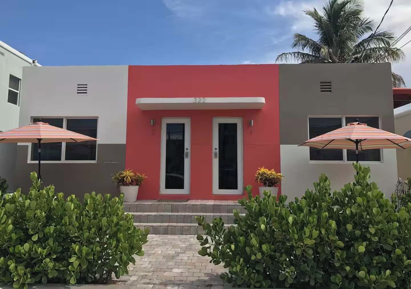 Um edifício moderno com fachada vermelha, duas portas e duas janelas com guarda-chuvas.