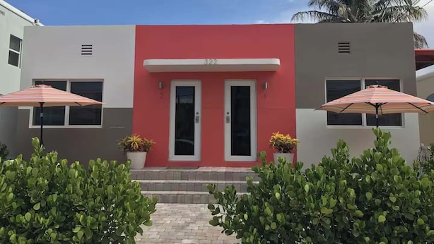 Un bâtiment moderne à la façade rouge, doté de deux portes et de deux fenêtres ornées de parapluies.