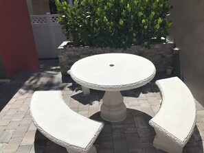 A white outdoor table with two curved benches, surrounded by a brick patio. - Beachside Comfort 2BR and 2BA  with Outdoor Dining (Hollywood)