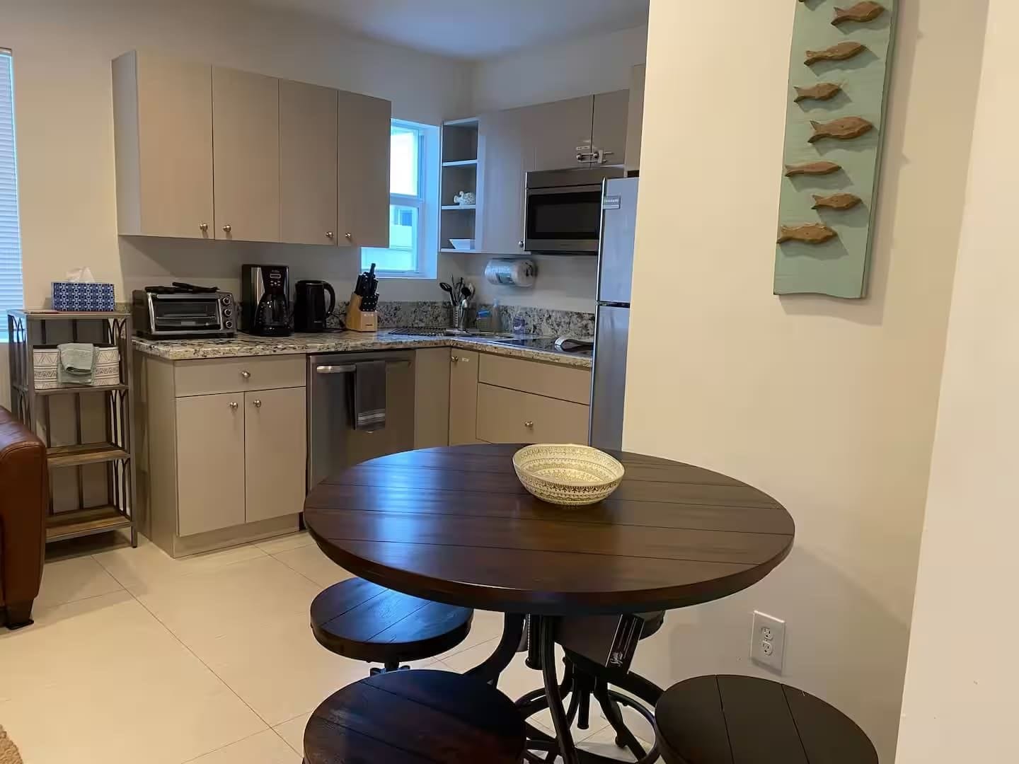 Una cocina moderna con una mesa de comedor y taburetes, horno empotrado y microondas.
