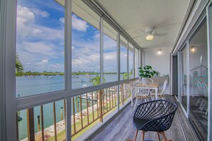 Ein Balkon mit Blick auf eine Marina, ein Esstisch mit Stühlen und ein Deckenventilator.