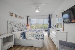 Ein Schlafzimmer mit einem Bett, einem Schminktisch, einem Fernseher und einem Deckenventilator.