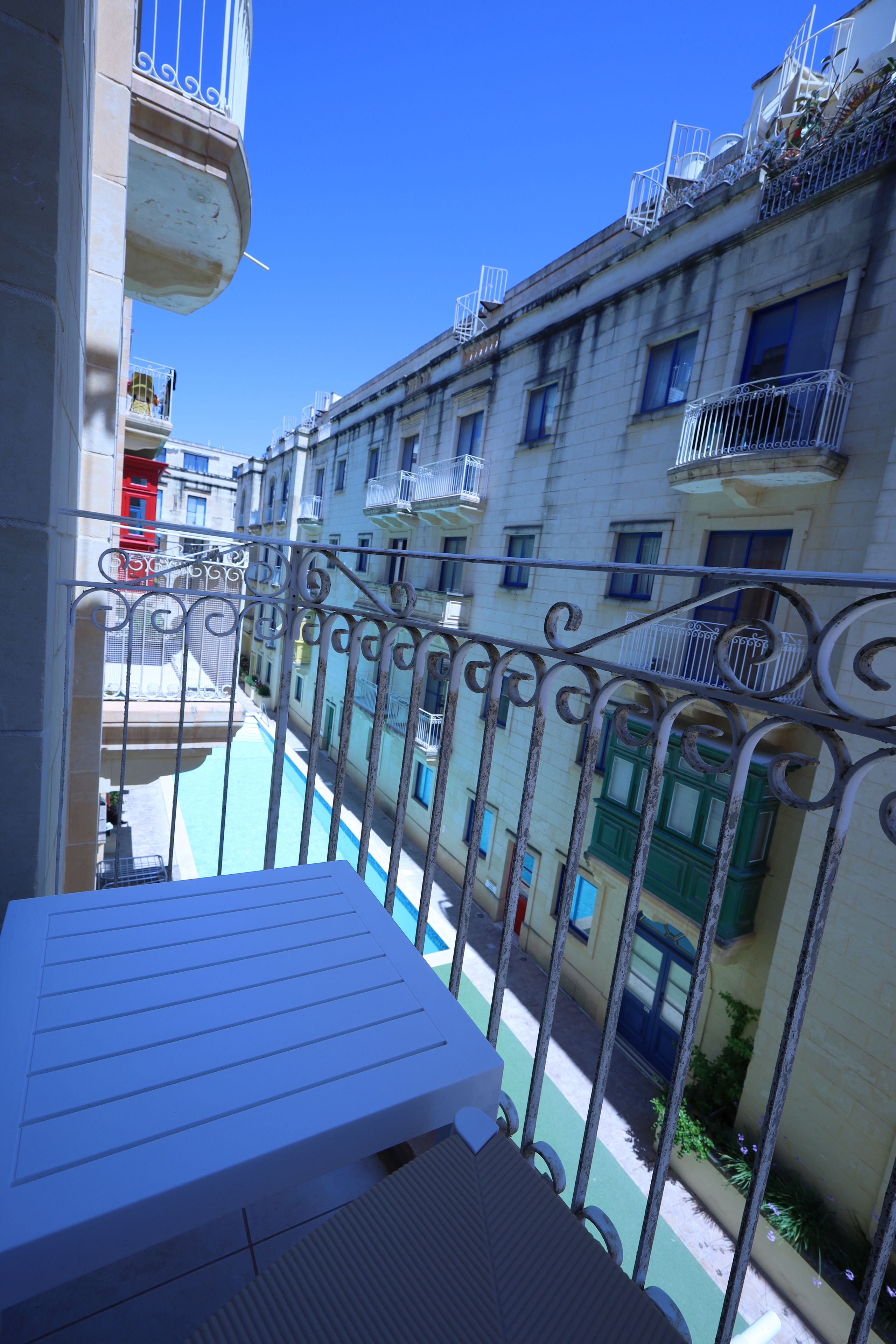 Een balkon met uitzicht op een zwembad en omliggende gebouwen.
