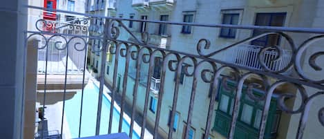 A balcony with a view of a swimming pool and adjacent buildings.
