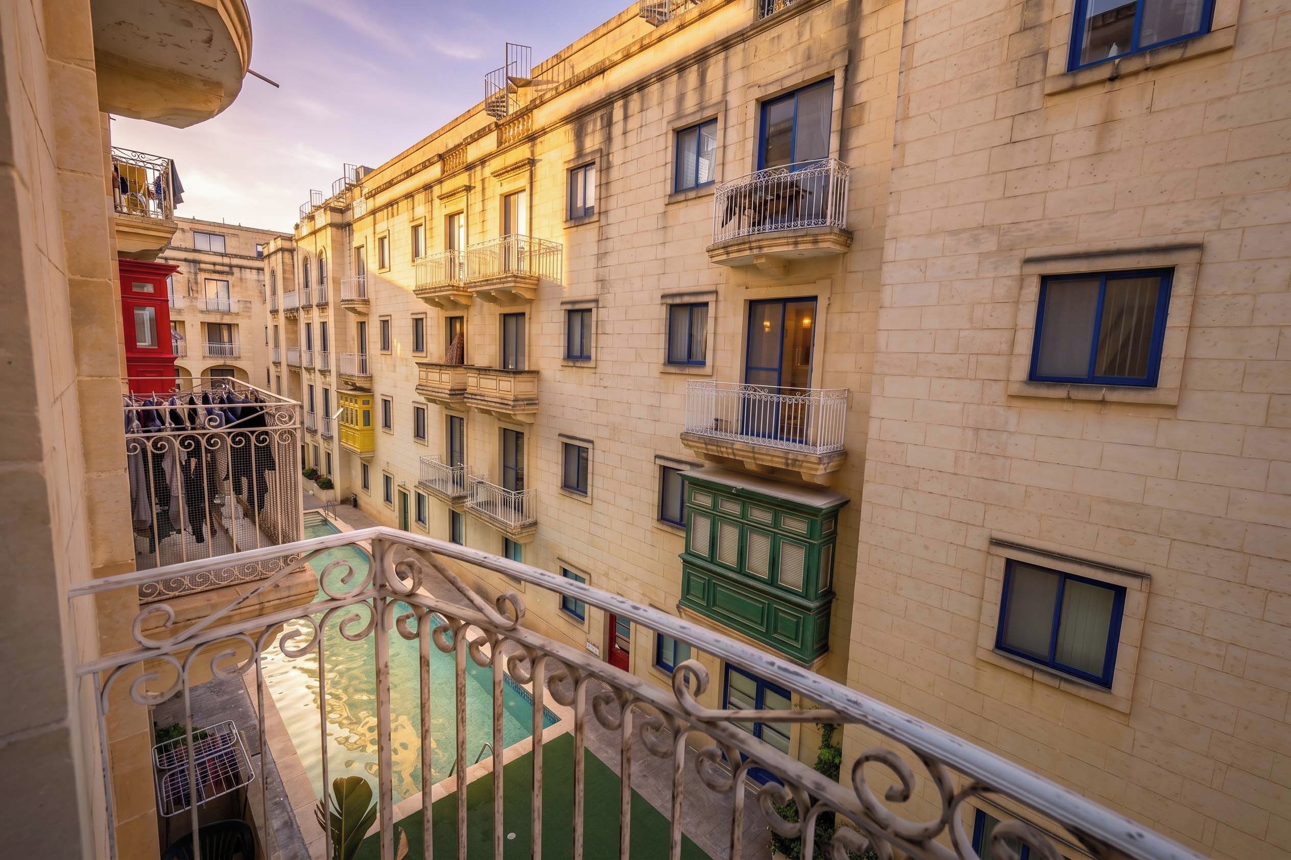Un edificio a più piani con balconi, un cortile interno e una piscina.