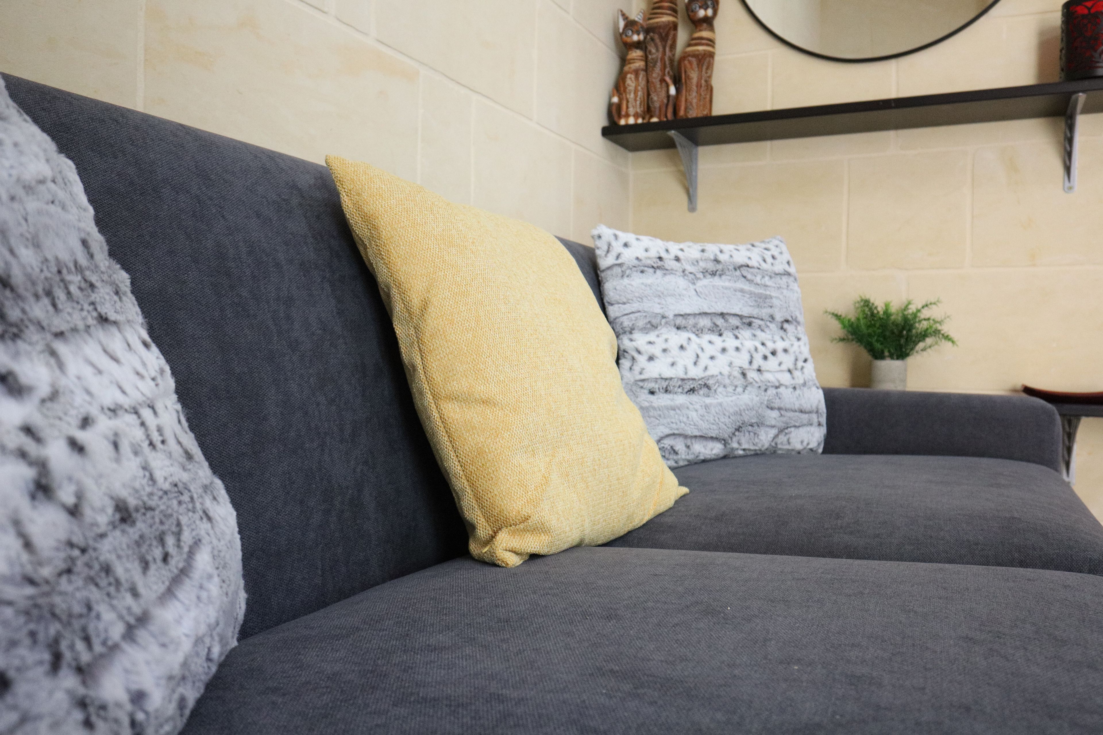 A grey sofa with three cushions in a living room.