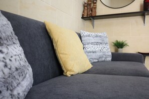 A grey sofa with three cushions in a living room.