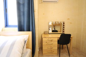 A bedroom with a bed, a wooden desk with a mirror, and a chair.