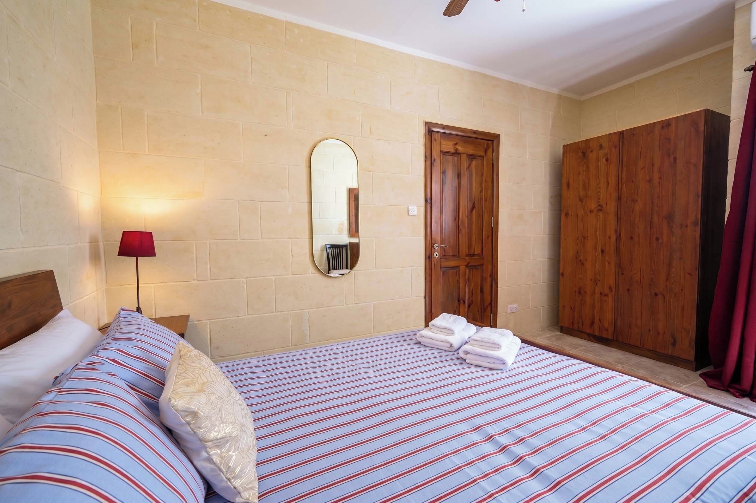 Habitación de hotel con dos camas, un armario de madera, un espejo y una lámpara roja.