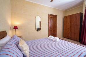 A hotel room with two beds, a wooden wardrobe, a mirror, and a red lamp.