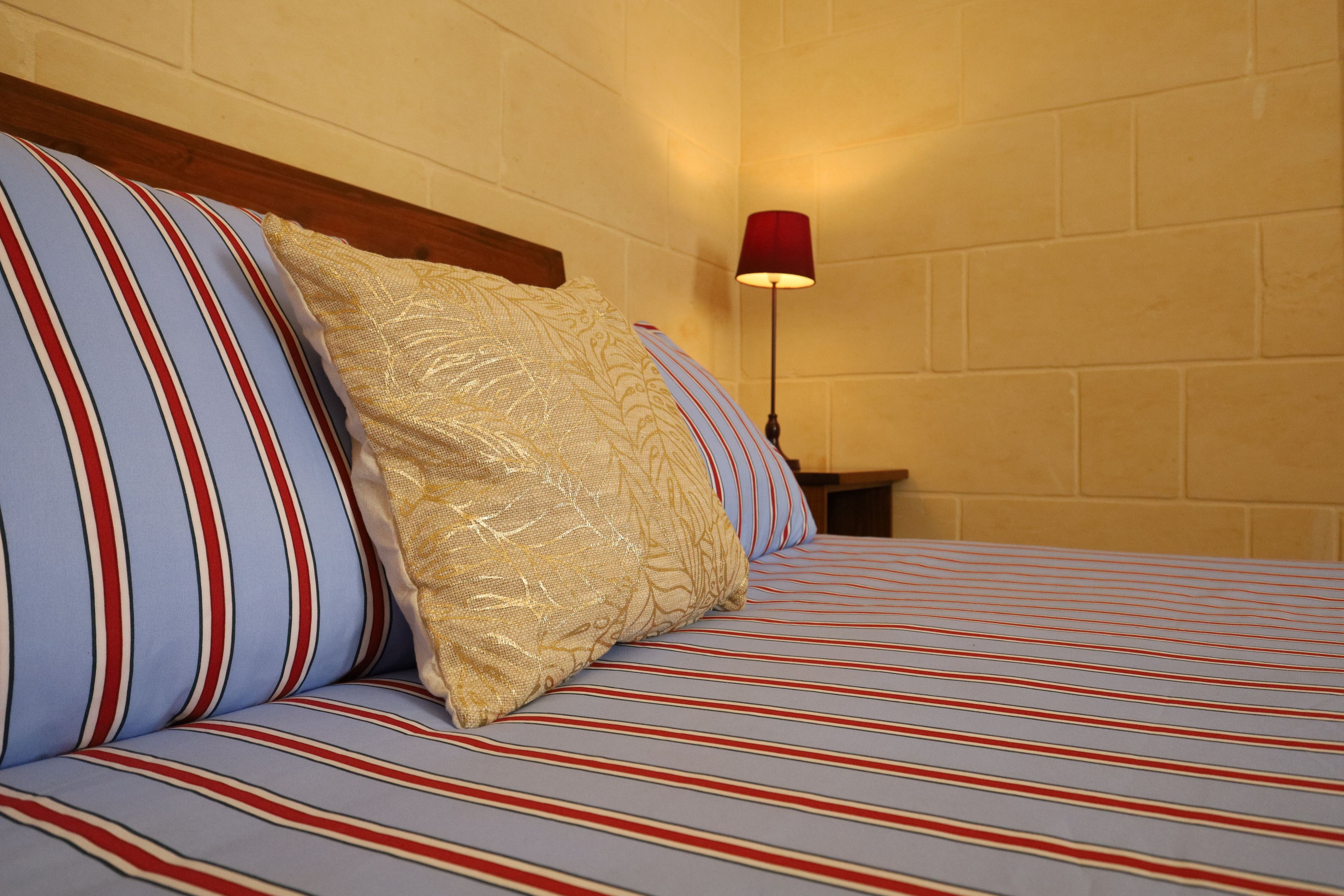 Un lit avec une literie à rayures et un seul coussin décoratif.