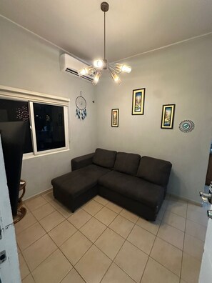 Ein Wohnzimmer mit Ecksofa, Deckenventilator und Wandklimaanlage.