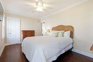 A bedroom with a bed, a dresser, a ceiling fan, and a door. - Moody Surfer - Coastal Retreat (Wells)