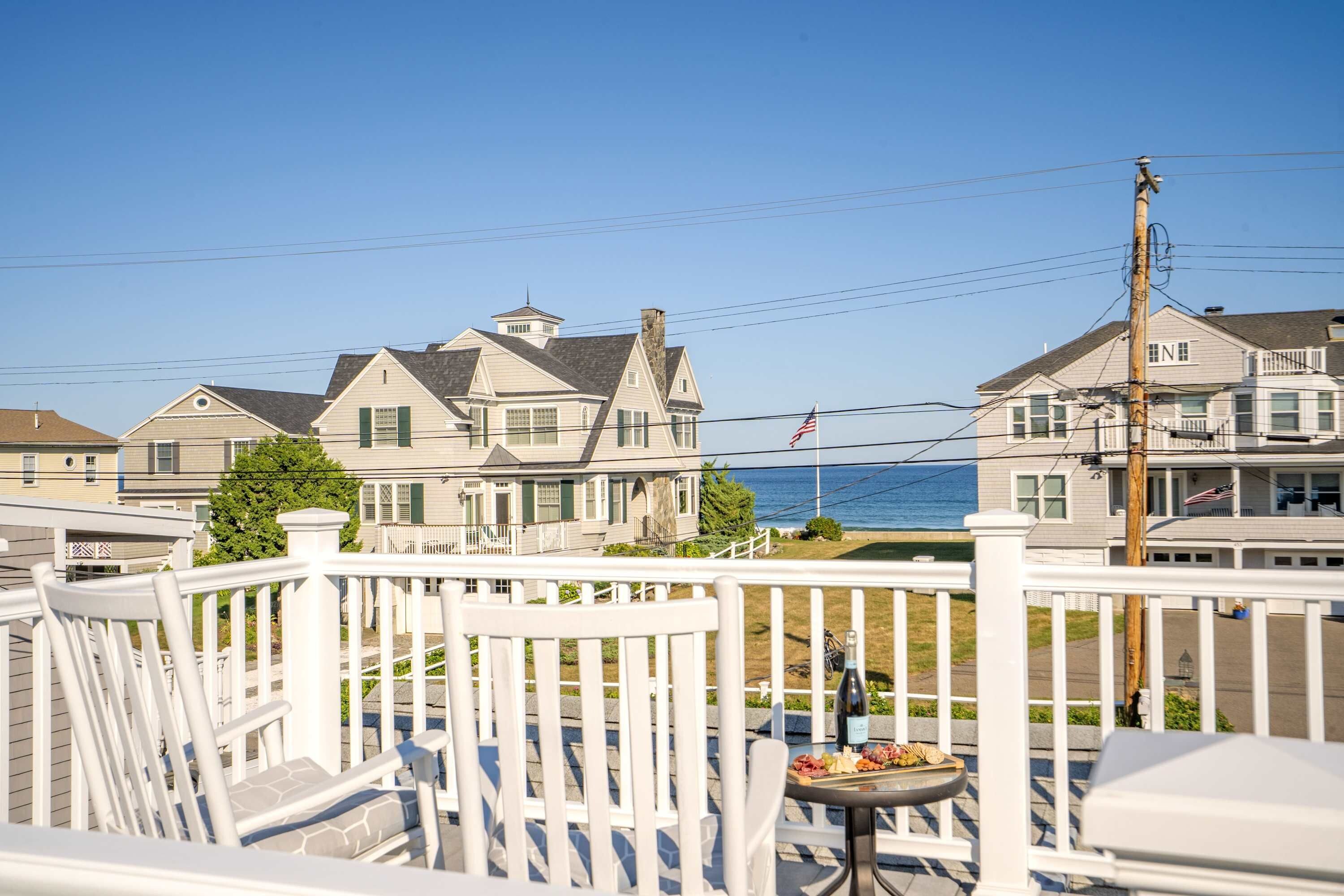 A coastal residential area with houses, a clear sky, and a view of the ocean.