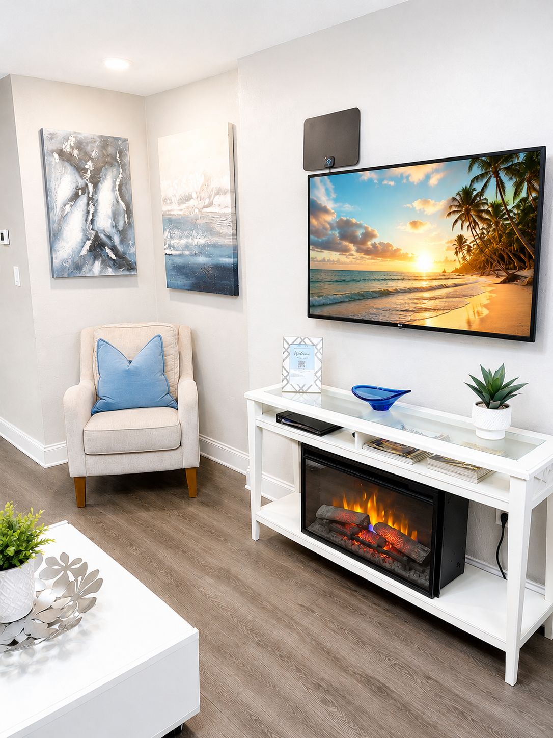 Een woonkamer met een open haard, een aan de muur bevestigde televisie en een fauteuil met een kussen.