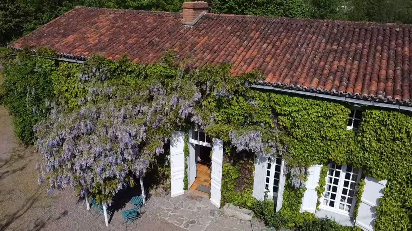 Un edificio con tetto in tegole rosse, cornici delle finestre bianche e un ingresso coperto.