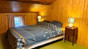 Una habitación con paneles de madera, una cama, dos lámparas de noche y un ventanal con cortinas.