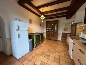 A kitchen with a white refrigerator, a green cabinet, a wooden cabinet with glass doors, and a tiled floor.