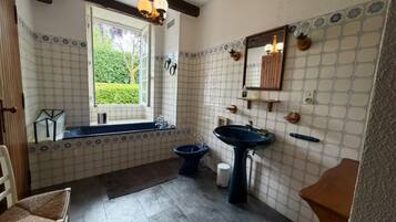 Een badkamer met een bad, een wastafel en een raam.