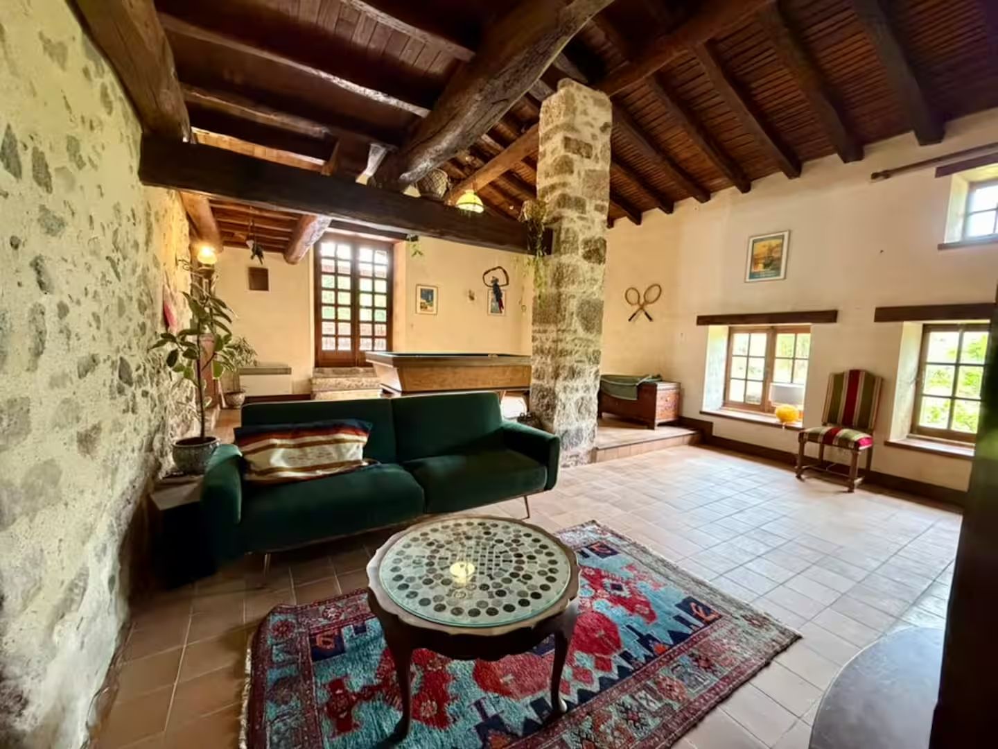 Un intérieur rustique avec un canapé vert, un tapis à motifs et une table ronde.