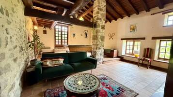 Un intérieur rustique avec un canapé vert, un tapis à motifs et une table ronde.