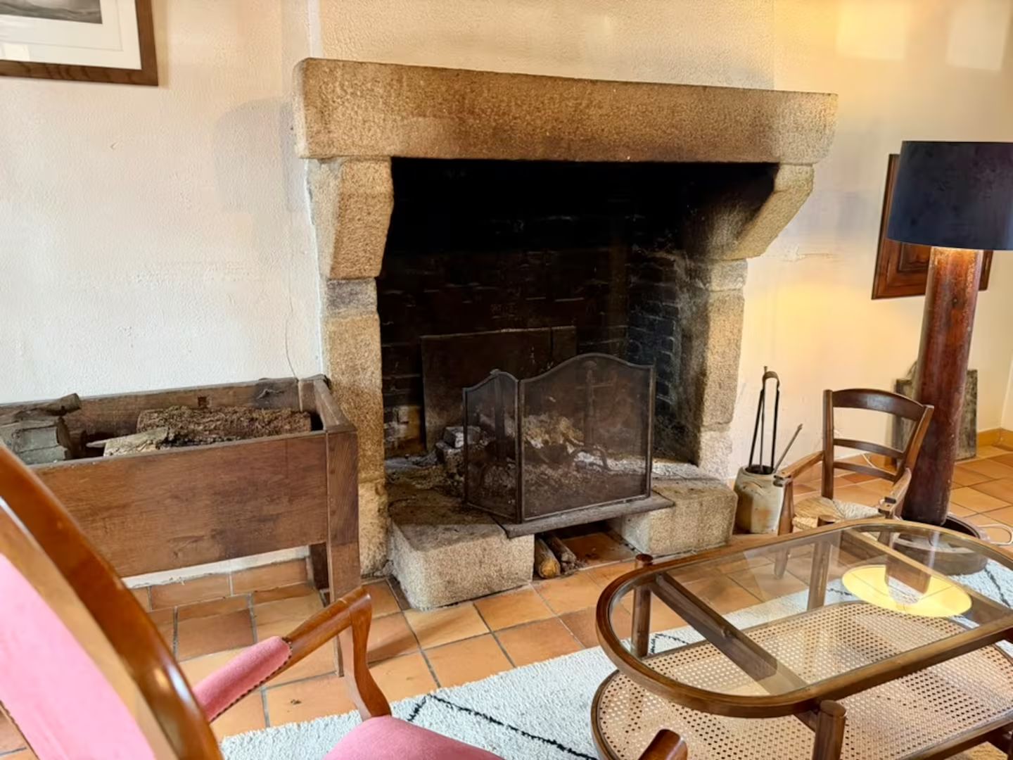 Una sala de estar con chimenea de piedra, una mesa de centro de vidrio y un banco de madera.