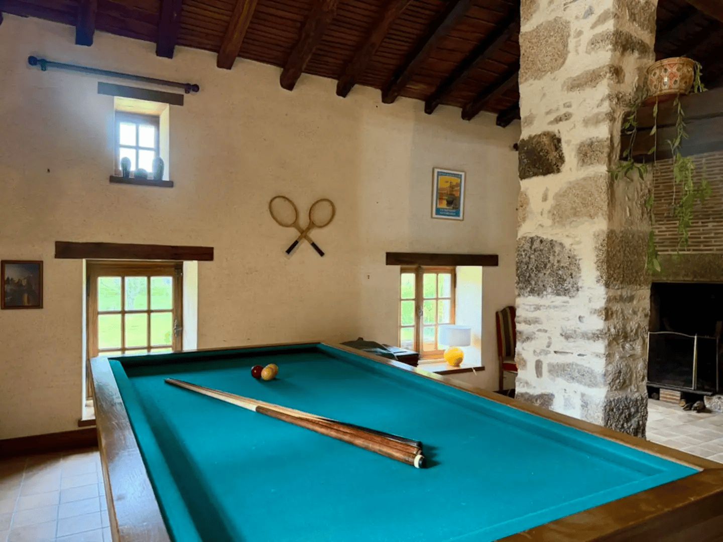 A pool table with a cue stick, two billiard balls, and a pair of scissors on the wall.