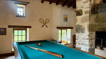 A pool table with a cue stick, two billiard balls, and a pair of scissors on the wall.