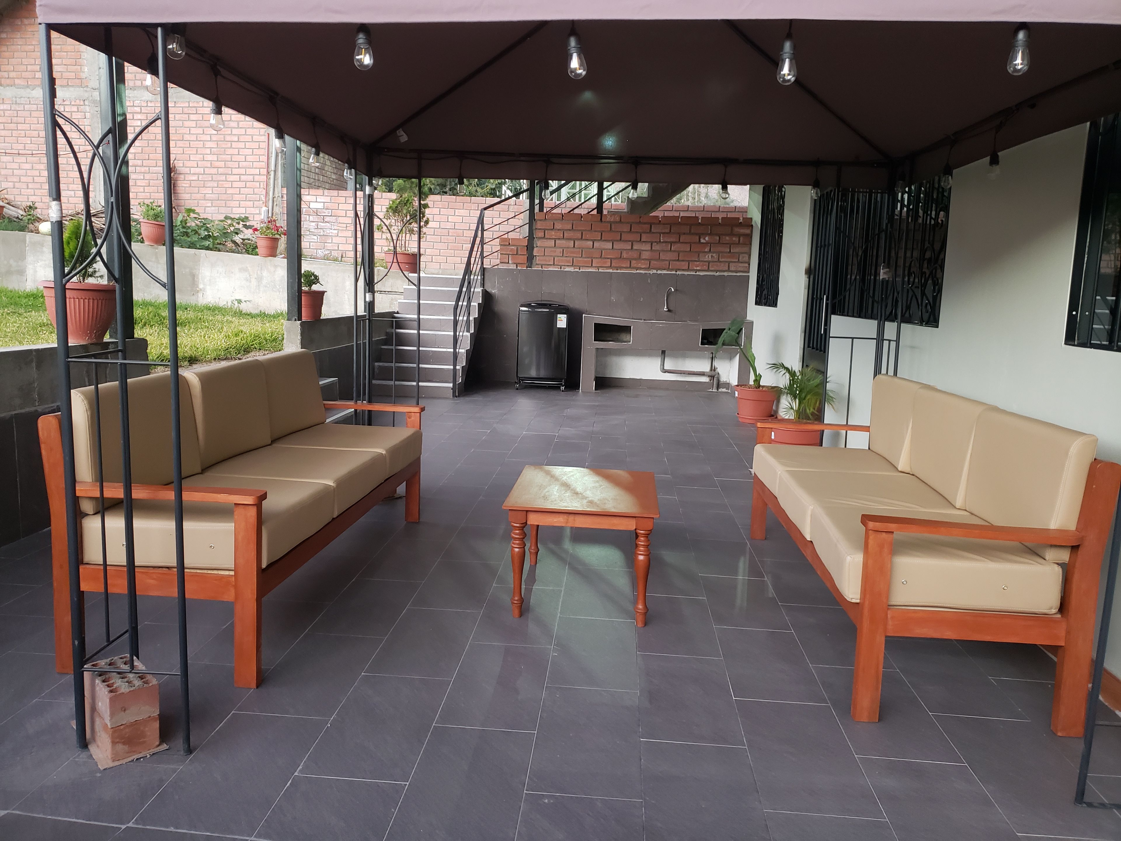 Un espacio al aire libre con un patio que tiene dos sofás, una mesa y una parrilla.