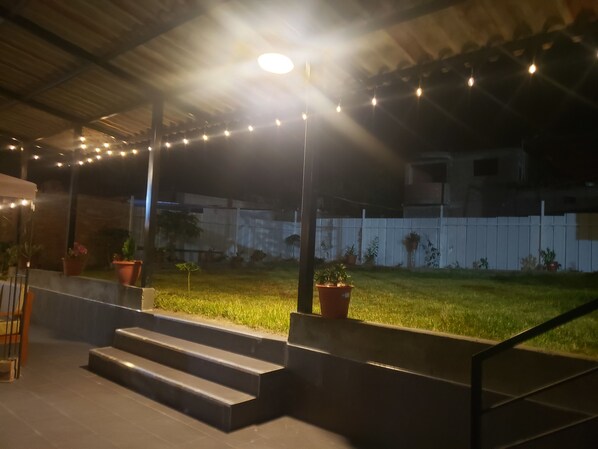 An outdoor area with steps leading to a covered patio, string lights, and potted plants.