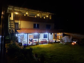 Un edificio de dos pisos con un patio techado, asientos exteriores y una chimenea.