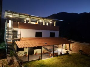 Una casa de dos pisos con balcón, patio cubierto y escalera.